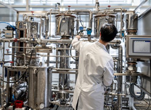 Back view of male student working at the process lab distilling liquids - Education concepts